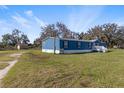A blue mobile home sits on a large grassy lot with a storage shed on the property at 8428 Highland Pines Ct, Plant City, FL 33565
