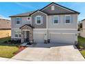 Two story home with a two car garage, light gray paint, stone entryway and shutters on the windows at 8816 Mugnai St, Riverview, FL 33578