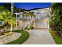 Lovely two-story home with a white staircase leading to a balcony, surrounded by lush palm trees at 1051 Point Seaside, Crystal Beach, FL 34681