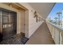 Condo entryway showcasing the exterior corridor, unit door, lighting fixtures, and waterfront view at 131 Bluff View Dr # 208, Belleair Bluffs, FL 33770