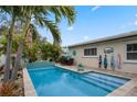Sparkling blue pool area complete with a waterfall feature, tropical landscaping, and patio seating at 1350 Maple Sw St, Largo, FL 33770