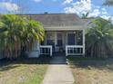 Inviting covered front porch with neutral siding and blue door, framed by lush palm trees on either side at 2218 Egret Walk Ct, New Port Richey, FL 34655
