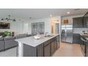 Kitchen island with sink and seating, stainless steel fridge, open floor plan to living room at 10348 Cross River Trl, Parrish, FL 34219