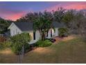 Dusk view of exterior showcases the home's well-maintained landscaping and charming facade at 10925 Fort King Rd, Dade City, FL 33525