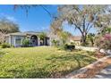 Well-maintained home exterior with lush green lawn, mature trees, and colorful landscaping at 2823 Clubhouse Dr, Plant City, FL 33566