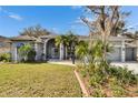 Charming single-story home with a well-manicured lawn, landscaped garden, and a gray exterior at 2823 Clubhouse Dr, Plant City, FL 33566