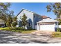 Two-story home showing a side view of the garage, well-maintained lawn, and mature trees at 4301 W San Luis St, Tampa, FL 33629