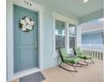 Inviting front porch with seating, charming door, and decorative wreath at 704 Winterside Dr, Apollo Beach, FL 33572