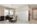Elegant dining room boasting a modern chandelier, wainscoting, and a table for six with upholstered chairs at 11930 Perennial Pl, Bradenton, FL 34211