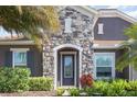 Close-up of a stone facade and front door with leaded glass sidelights surrounded by lush landscaping at 11930 Perennial Pl, Bradenton, FL 34211
