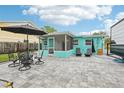 Backyard patio features outdoor seating, a screened-in porch, lush landscaping, and ample space for entertaining at 1868 Douglas Ave, Dunedin, FL 34698