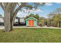 Backyard shed provides storage space with a unique design and is surrounded by a firepit area and mature trees at 1868 Douglas Ave, Dunedin, FL 34698
