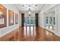 Formal Living Room featuring French Doors to pool, hardwood floors, chandelier and tray ceiling at 19238 Climbing Aster Dr, Tampa, FL 33647