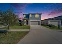 Attractive two-story home featuring a spacious driveway, well-manicured lawn and blue and gray facade at dusk at 3204 Fresno Pl, Zephyrhills, FL 33541