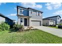 Charming two-story home with a gray two car garage, well-maintained lawn, and neat landscaping at 3204 Fresno Pl, Zephyrhills, FL 33541