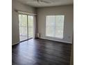 Well-lit living room with sliding glass doors to balcony and modern dark floors at 4211 Chatham Oak Ct # 122, Tampa, FL 33624