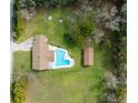 Aerial view of the property featuring a pool, detached building and surrounded by lush greenery and trees at 555 Hickory St, Brooksville, FL 34601