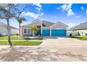Charming single-Gathering home featuring a three-car garage and eye-catching turquoise doors at 13235 Graham Yarden Dr, Riverview, FL 33579