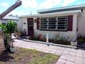 Inviting home exterior showcasing a brick facade, well-manicured front yard and walkway at 14034 Marguerite Dr, Madeira Beach, FL 33708