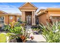 Inviting home entrance with vibrant landscaping, stone pathway, and a covered porch with decorative columns at 16410 Ivy Lake Dr, Odessa, FL 33556