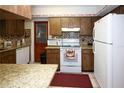 A view of the kitchen with white appliances, wood cabinetry, and granite countertops at 204 Amana Ave, Brandon, FL 33510