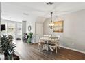 Cozy dining room featuring wood floors, a chandelier and neutral paint with access to the living room at 6134 Fishhawk Crossing Blvd, Lithia, FL 33547