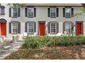 Townhome exterior with red door, black shutters and window trim with lush green foliage at 6134 Fishhawk Crossing Blvd, Lithia, FL 33547