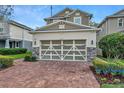 Charming two-story home featuring a brick driveway, beautiful landscaping, and a modern garage door at 8297 Artisan Way, Seminole, FL 33777