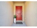 Inviting front entryway with a red door, potted plant, and clean, modern aesthetic at 8949 Southern Charm Cir, Brooksville, FL 34613