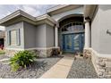 Elegant home entrance with stone accents, arched window, and a beautiful blue double door at 1547 Daylily Dr, Trinity, FL 34655