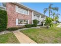 Two-story condo featuring a brick facade, lush landscaping, and inviting walkway at 211 Brandy Wine Dr # 211, Largo, FL 33771