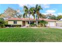 Inviting one-story home features a well-manicured lawn and mature landscaping at 220 Garden S Cir, Dunedin, FL 34698