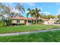 Attractive one-story home showcases a lush green lawn, tropical plants, and a paver walkway at 220 Garden S Cir, Dunedin, FL 34698