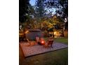 A backyard featuring a fire pit with Adirondack chairs, a shed and a pergola-covered seating area, all lit with string lights at 2454 15Th N Ave, St Petersburg, FL 33713