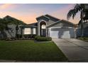 Charming single Gathering home with a well maintained lawn and beautiful Florida landscaping at sunset at 31101 Wrencrest Dr, Wesley Chapel, FL 33543