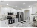 Modern kitchen featuring stainless steel appliances, white cabinetry, and elegant countertops with a sink at 10424 Gifford Dr, Spring Hill, FL 34608