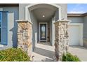 Inviting front door with stone columns and a warm welcome sign, offering a charming entryway at 10920 Green Harvest Dr, Riverview, FL 33578