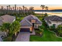 Beautiful lakefront home featuring a tile roof, brick driveway, two-car garage, and lush landscaping at 11720 Bitola Dr, Odessa, FL 33556