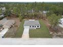 Aerial view of single-story home shows its neutral paint, and a two-car garage surrounded by mature trees and a well-maintained lawn at 12341 Filbert Rd, Weeki Wachee, FL 34614