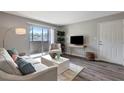 Open living room with light gray walls, wood floors, a modern sofa, and access to the balcony at 1400 Gandy N Blvd # 502, St Petersburg, FL 33702