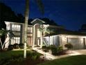 Charming two-story home with a well-manicured lawn and lush landscaping illuminated at dusk at 15702 Muirfield Dr, Odessa, FL 33556