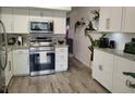 This kitchen offers white cabinetry, stainless steel appliances, granite counters and hardwood floors at 2256 Spanish Dr # 42, Clearwater, FL 33763