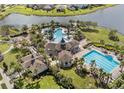 An aerial view showcasing the community pools, clubhouse, and a tranquil lake, surrounded by lush landscaping at 9313 Channing Hill Dr, Ruskin, FL 33573