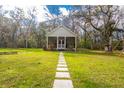 Inviting cottage-style home with a stone path leading to the screened porch in a serene setting at 13381 Glory Ln, Brooksville, FL 34614