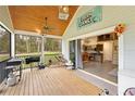 Large screened porch with wood ceiling, grill, and dining area, transitioning to a modern kitchen at 13381 Glory Ln, Brooksville, FL 34614