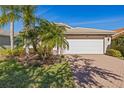 Exterior view of home featuring a two-car garage and beautiful landscaping in the front yard at 16023 Golden Lakes Dr, Wimauma, FL 33598