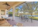 Covered and screened brick patio with outdoor seating overlooking a tranquil lake at 16023 Golden Lakes Dr, Wimauma, FL 33598