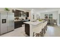 Bright open kitchen featuring an island with seating, stainless steel appliances, and dark wood cabinets at 17056 James Trl, Parrish, FL 34219