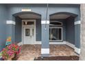 Covered front porch showcasing brick flooring, columns, decorative accents and charming front door at 17508 Isbell Ln, Odessa, FL 33556