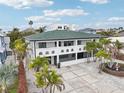 Eye-catching two-story home with a green roof, a white exterior, and beautiful landscaping with palms at 2710 Hibiscus W Dr, Belleair Beach, FL 33786